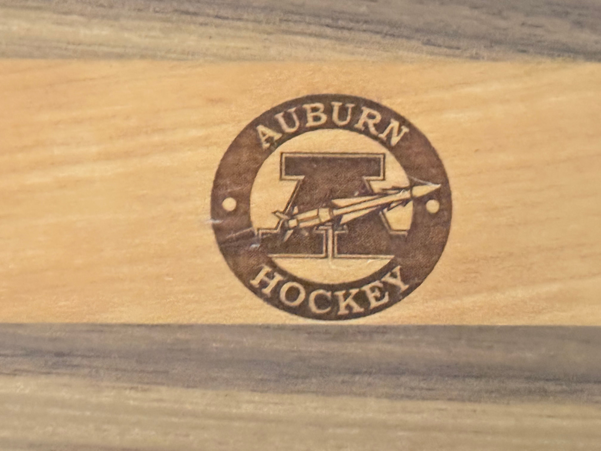 Close-up of the Auburn Hockey brand burned into the maple stripe